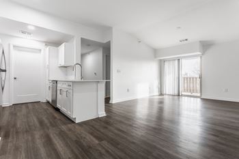 The living room and kitchen in a new home with white walls and wood flooring